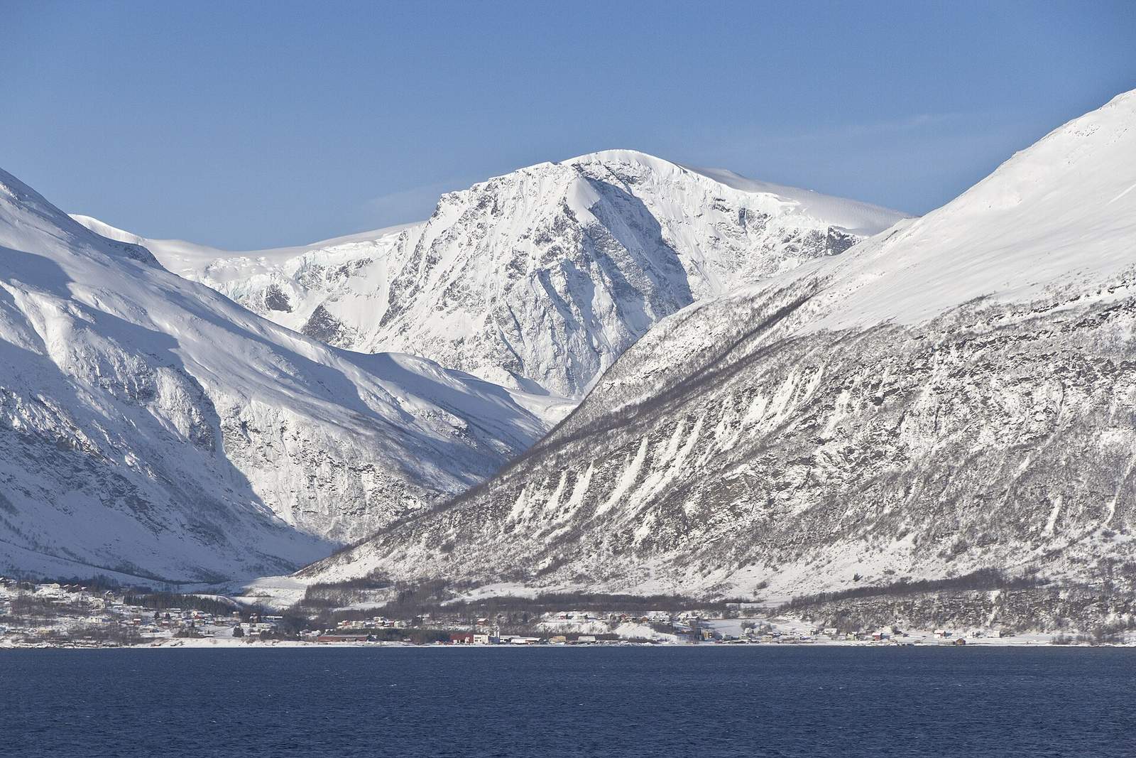 Snow-covered mountains rising from a dark fjord in the Lyngen area of northern Norway