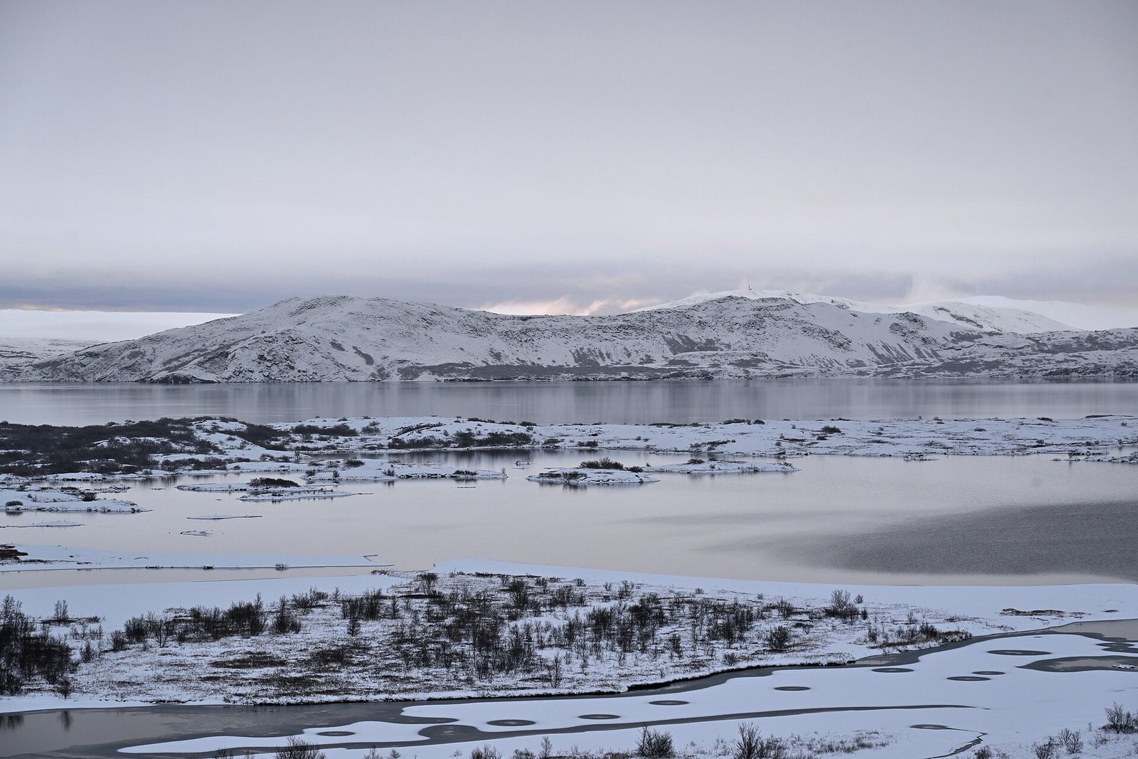 Snow on the shore of Lake Thingvallavatn in Iceland under a pale winter sky