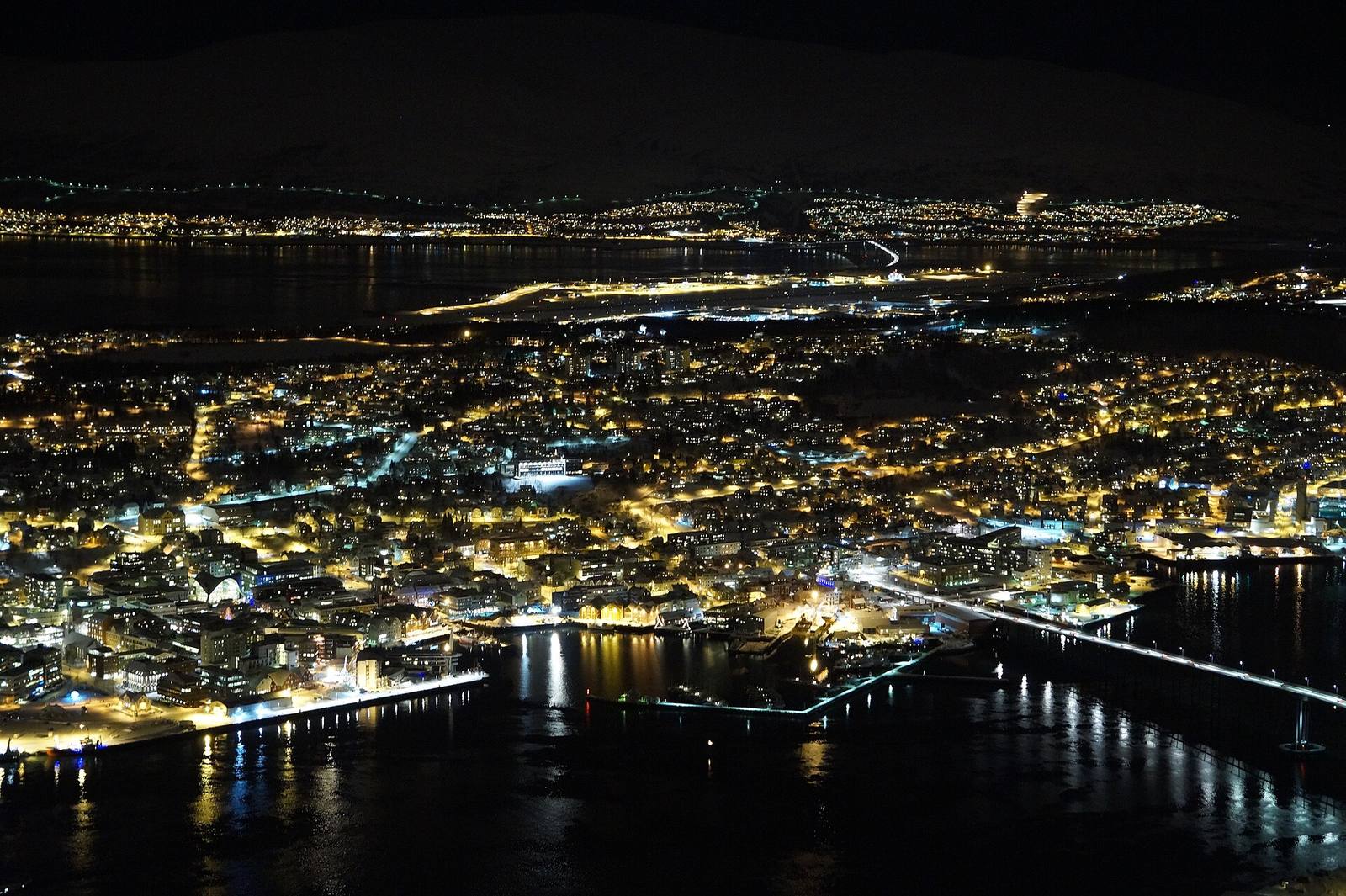 The lit streets and harbour of Tromsø seen from above at night